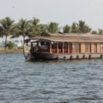 Traditional Kerala houseboat cruising through lush backwaters at sunset