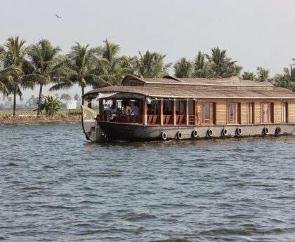 Traditional Kerala houseboat cruising through lush backwaters at sunset